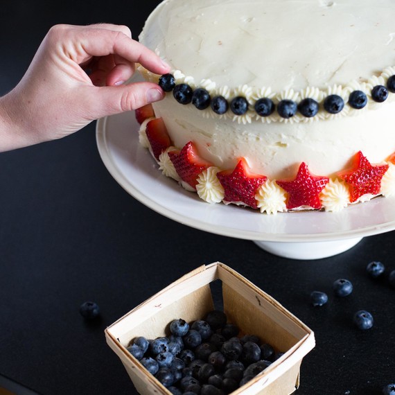 Affix strawberries and blueberries to cake